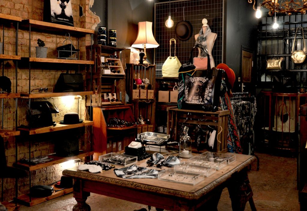 Vintage shop interior with hats, bags, jewellery and clothing displayed on shelves and tables in warm lighting